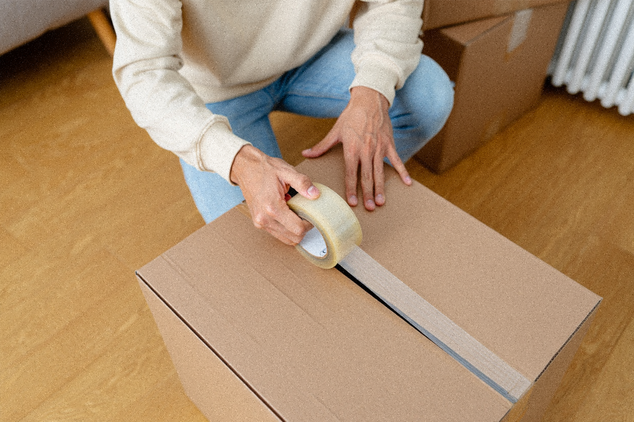 Man preparing to seal a moving box with using clear packing tape